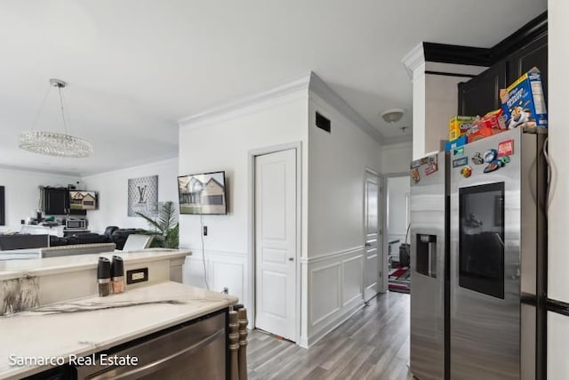 kitchen featuring a wainscoted wall, ornamental molding, wood finished floors, light countertops, and stainless steel refrigerator with ice dispenser