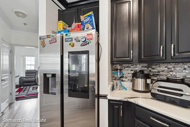 kitchen featuring decorative backsplash, stainless steel fridge with ice dispenser, wood finished floors, light countertops, and crown molding