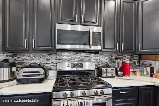 kitchen with light countertops, appliances with stainless steel finishes, dark cabinetry, and tasteful backsplash