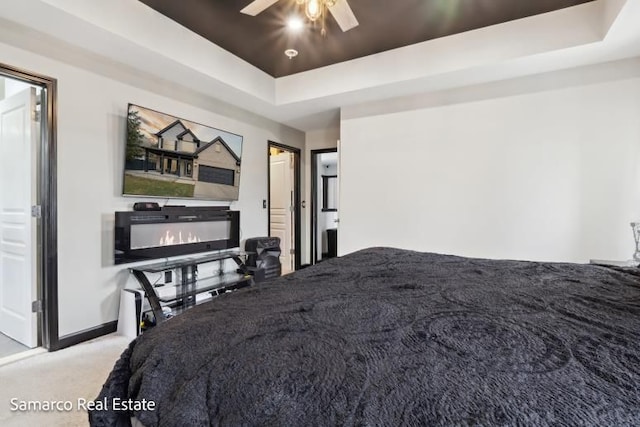 bedroom featuring carpet floors, baseboards, a raised ceiling, and a ceiling fan