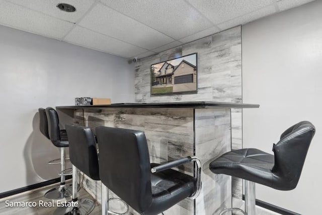 bar featuring a paneled ceiling, baseboards, and a dry bar