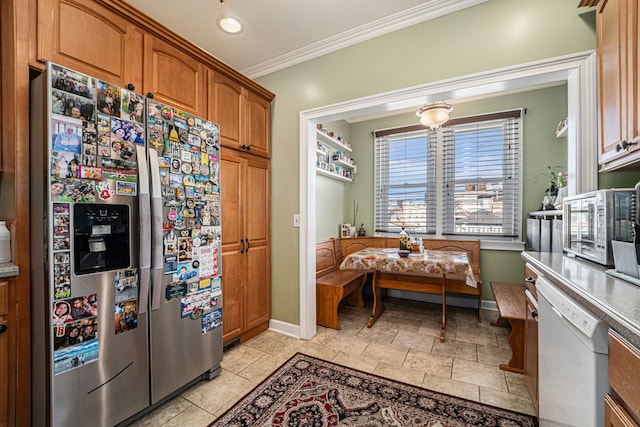 kitchen featuring brown cabinetry, baseboards, stainless steel appliances, and crown molding