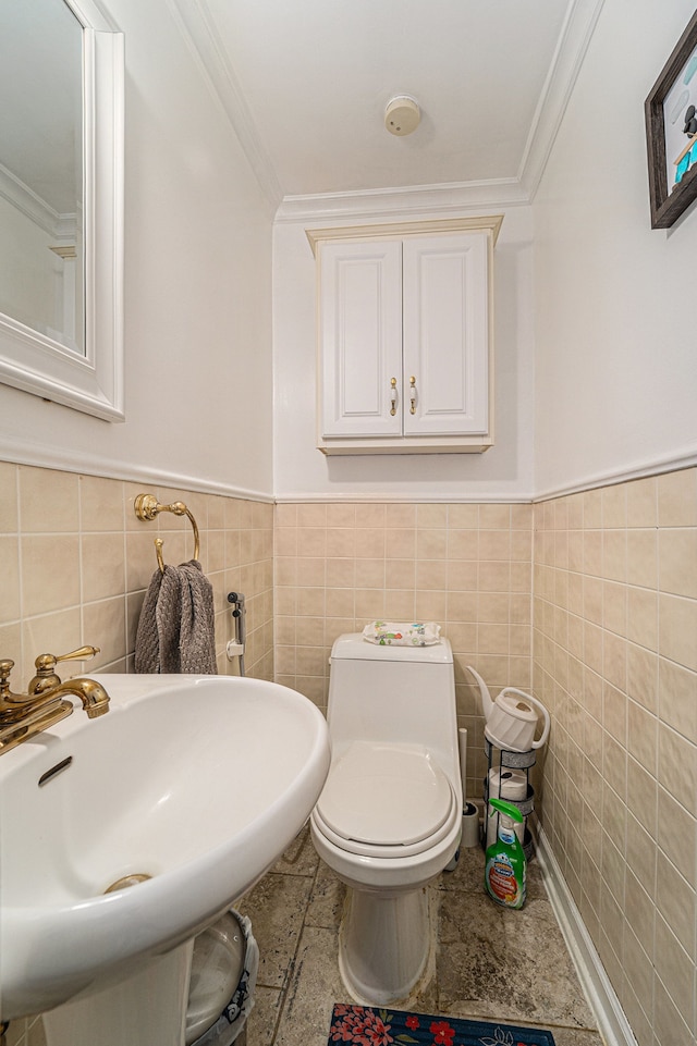 bathroom featuring a wainscoted wall, a sink, crown molding, and toilet