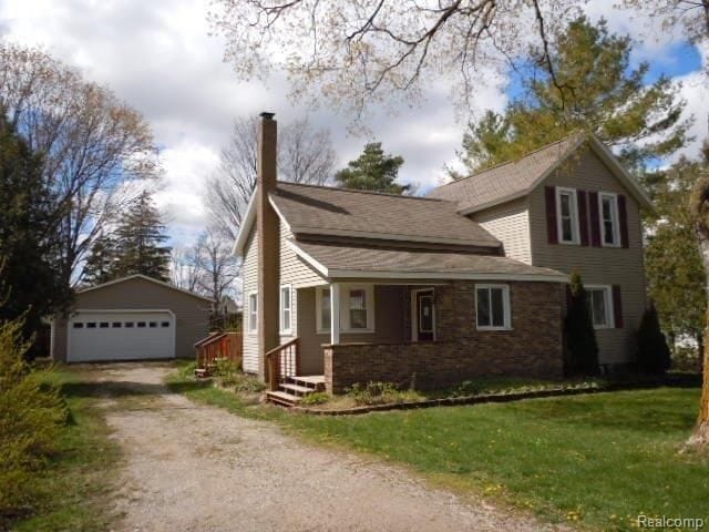 view of front of house with an outbuilding, a detached garage, a chimney, and a front yard