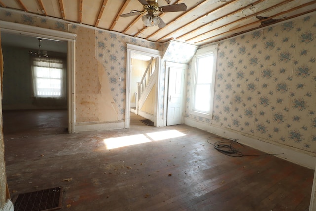 empty room with a wealth of natural light, visible vents, stairway, and wallpapered walls