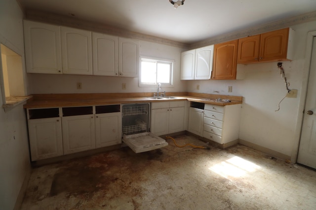 kitchen featuring tile patterned floors, a sink, white cabinets, and baseboards