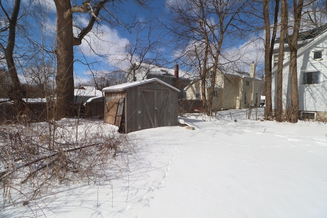 yard layered in snow featuring a storage shed and an outdoor structure