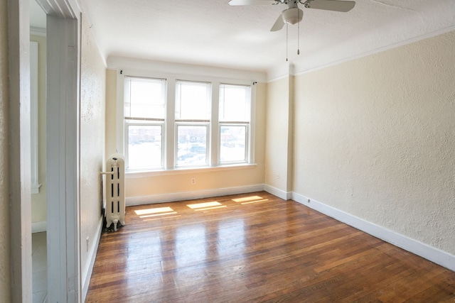 unfurnished room with baseboards, wood finished floors, and a textured wall