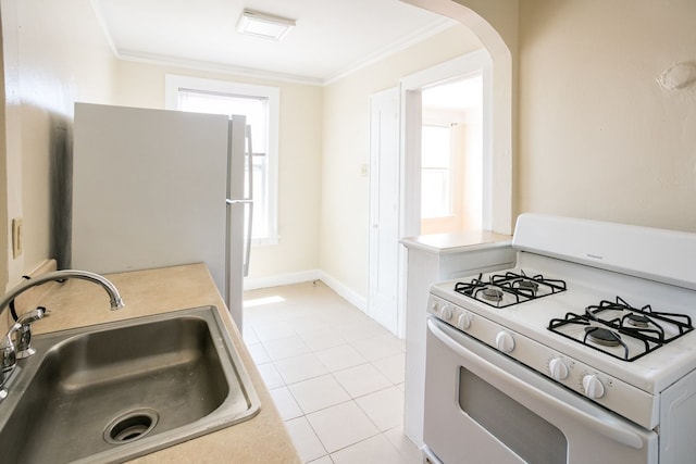 kitchen with white appliances, light tile patterned floors, ornamental molding, and a sink