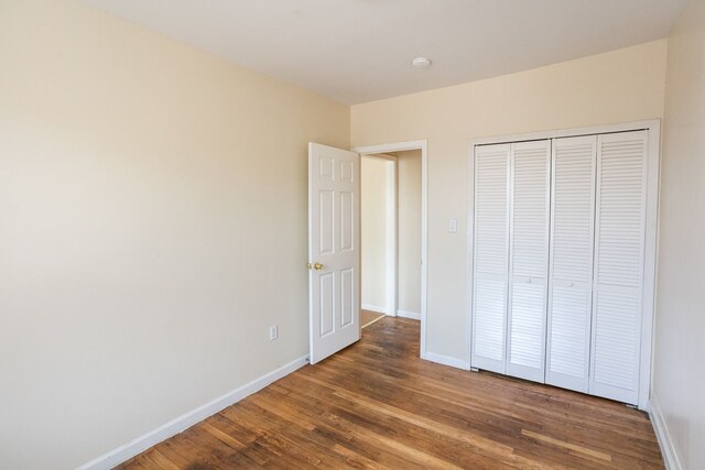 unfurnished bedroom featuring a closet, baseboards, and wood finished floors