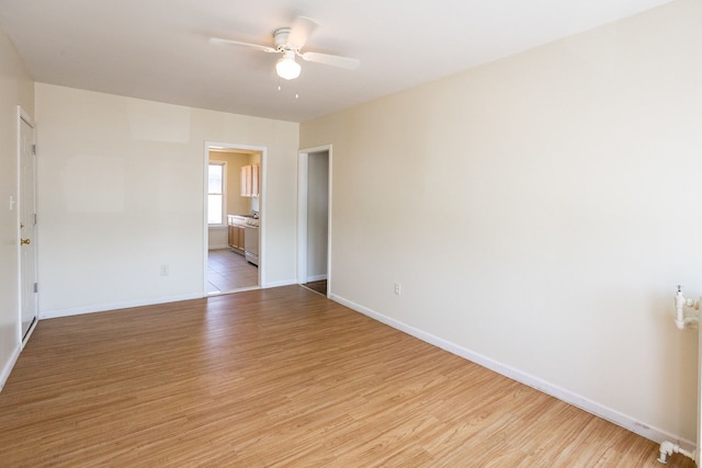 empty room featuring ceiling fan, light wood-style flooring, and baseboards