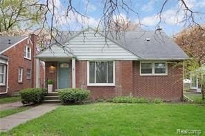 bungalow featuring a front yard and brick siding