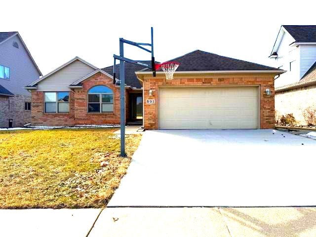 single story home with driveway, an attached garage, a front yard, and brick siding