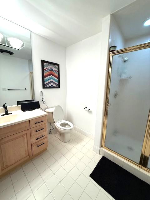 bathroom featuring a stall shower, tile patterned flooring, vanity, and toilet