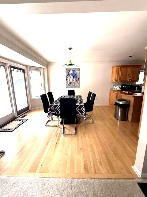 dining space featuring light wood-type flooring and crown molding