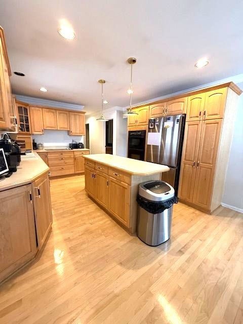 kitchen featuring freestanding refrigerator, a center island, light countertops, and light wood finished floors