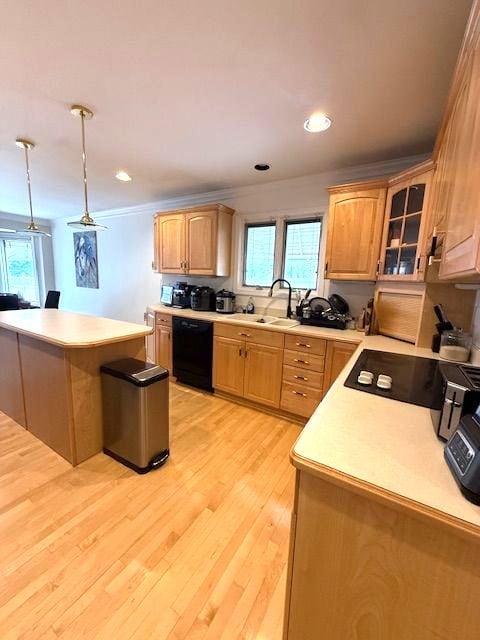 kitchen featuring black dishwasher, light wood finished floors, light countertops, glass insert cabinets, and a sink