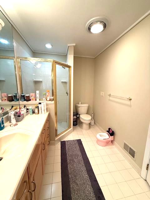 bathroom featuring toilet, vanity, visible vents, tile patterned floors, and a stall shower