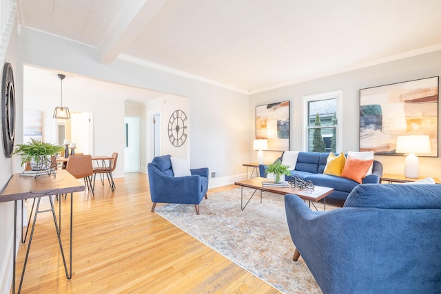 living room with ornamental molding, beam ceiling, light wood-style flooring, and baseboards