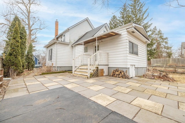 back of property featuring a patio area, a chimney, and fence