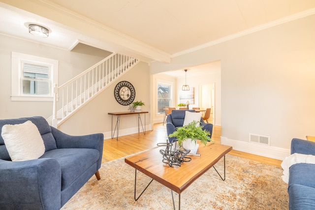 living area with ornamental molding, stairway, wood finished floors, and visible vents