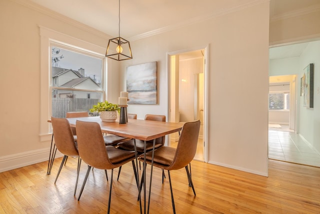 dining room featuring light wood-type flooring, baseboards, and ornamental molding