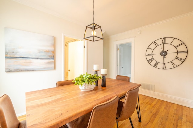 dining space with baseboards, light wood-type flooring, visible vents, and crown molding