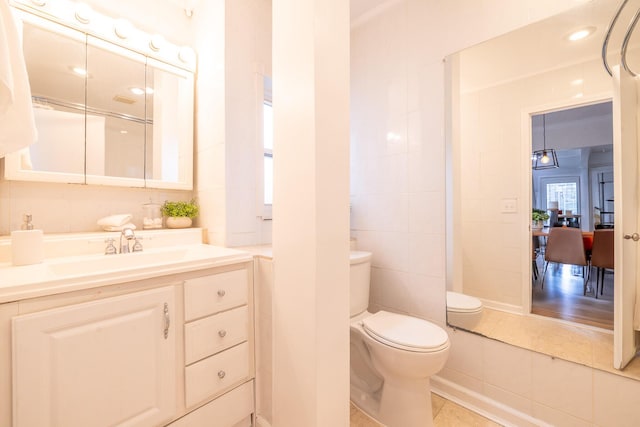 bathroom featuring tile patterned flooring, tile walls, vanity, and toilet