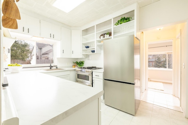 kitchen featuring open shelves, stainless steel appliances, light countertops, white cabinets, and a sink