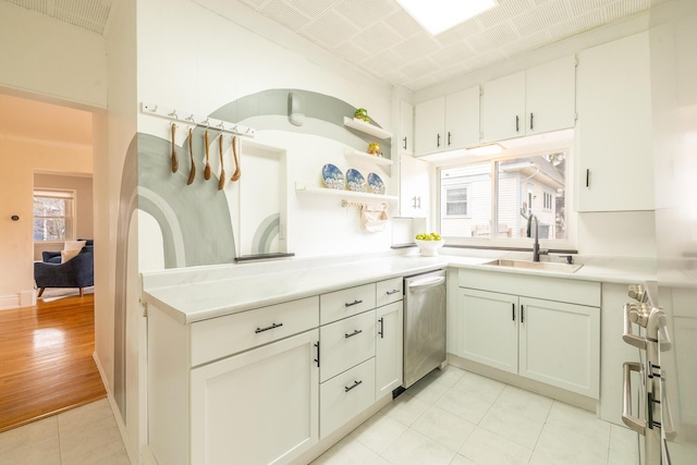 kitchen with light tile patterned flooring, a sink, white cabinets, light countertops, and dishwasher