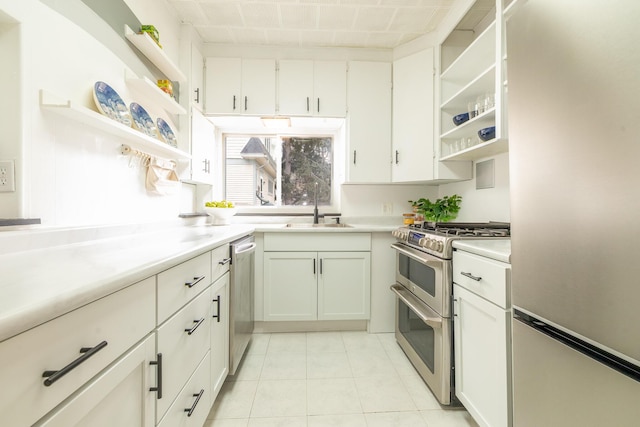 kitchen with stainless steel appliances, light countertops, white cabinetry, open shelves, and a sink