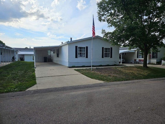 manufactured / mobile home featuring driveway, an attached carport, and a front yard