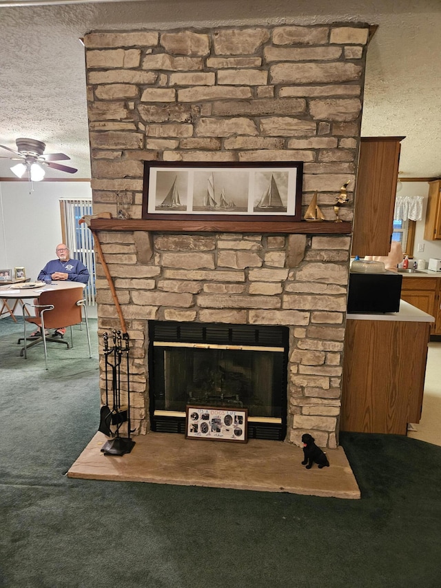 room details with a ceiling fan, a stone fireplace, carpet flooring, and a textured ceiling