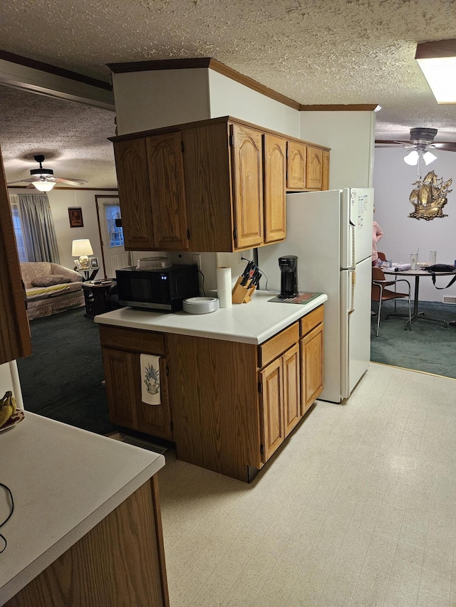 kitchen featuring light countertops, ornamental molding, ceiling fan, a textured ceiling, and black microwave