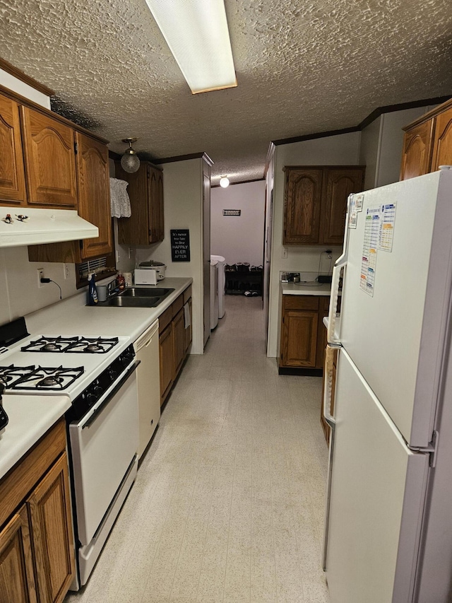 kitchen with under cabinet range hood, white appliances, a sink, light floors, and washer and clothes dryer