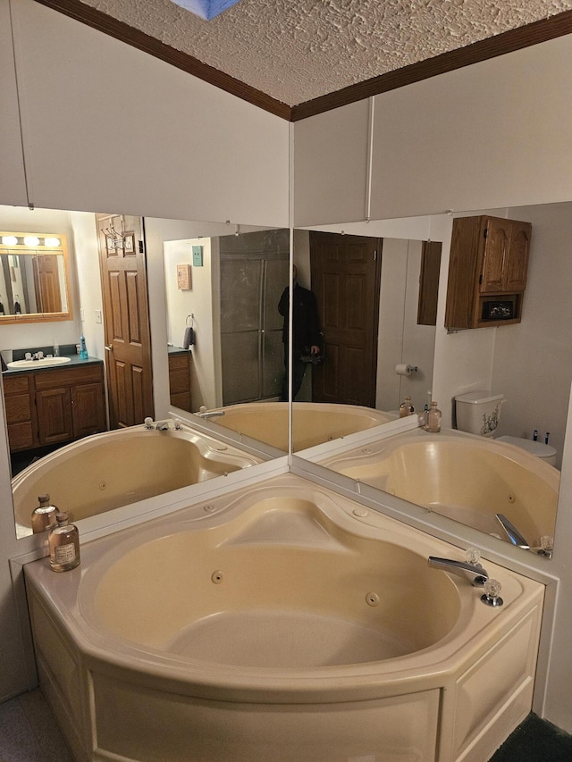 full bathroom with a jetted tub, a textured ceiling, and vanity