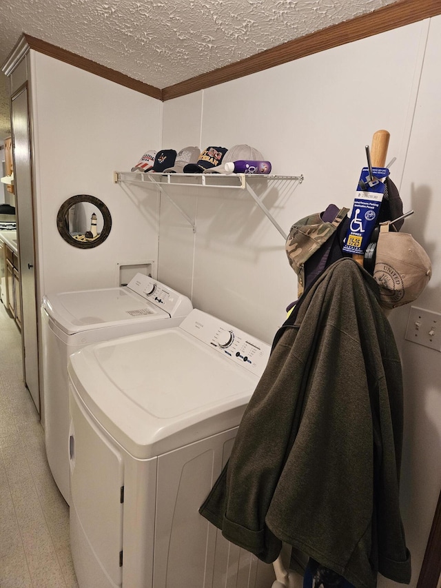 washroom with a textured ceiling, laundry area, washing machine and clothes dryer, and crown molding