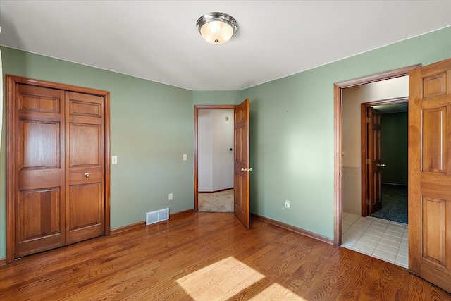 unfurnished bedroom featuring light wood-type flooring, visible vents, and baseboards