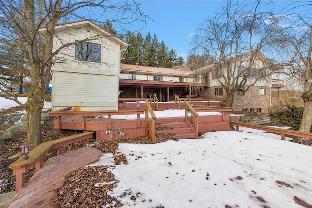 snow covered back of property with a deck