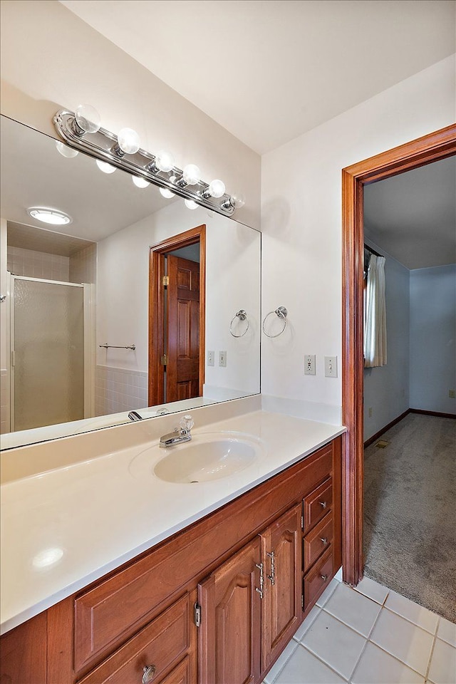 bathroom with a shower with shower door, tile patterned flooring, and vanity