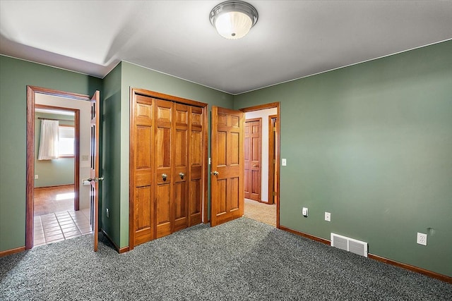 unfurnished bedroom featuring carpet floors, a closet, visible vents, and baseboards