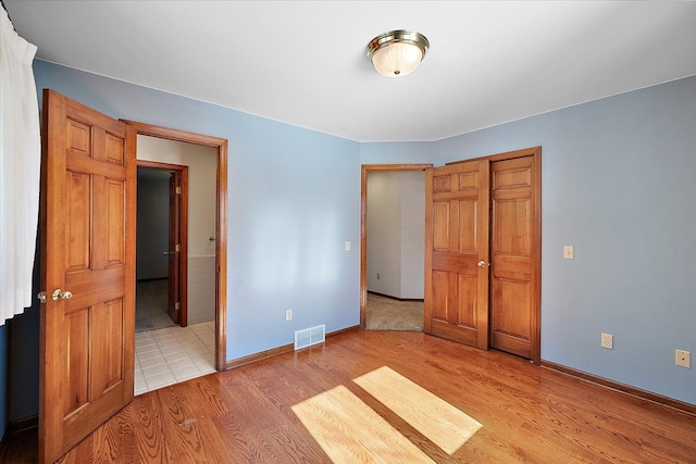 unfurnished bedroom featuring baseboards, visible vents, and light wood-style floors