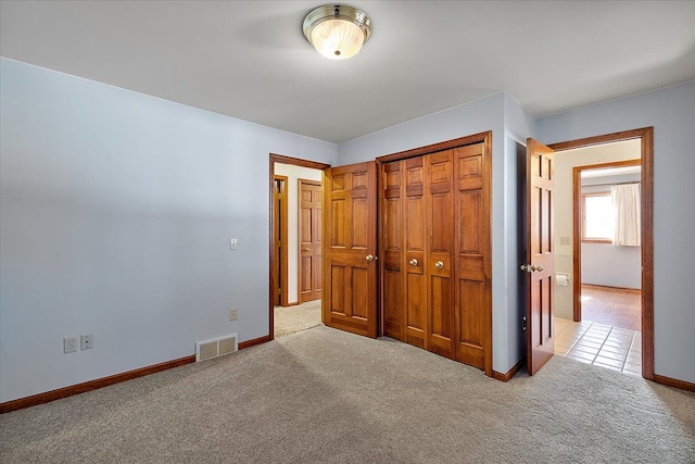 unfurnished bedroom featuring a closet, carpet flooring, visible vents, and baseboards