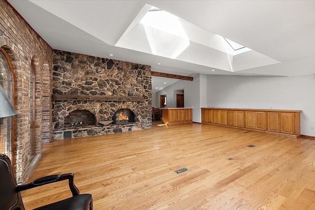 living room featuring a fireplace, light wood finished floors, recessed lighting, visible vents, and vaulted ceiling