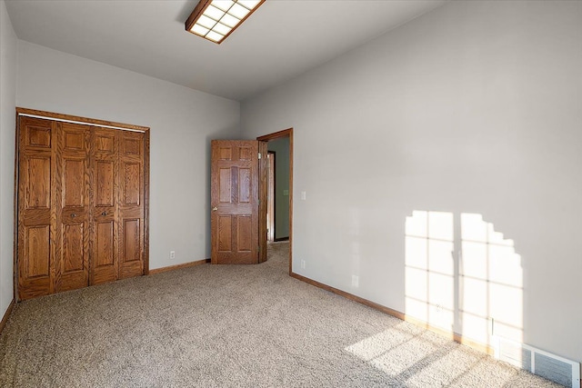 unfurnished bedroom with lofted ceiling, carpet, visible vents, and baseboards