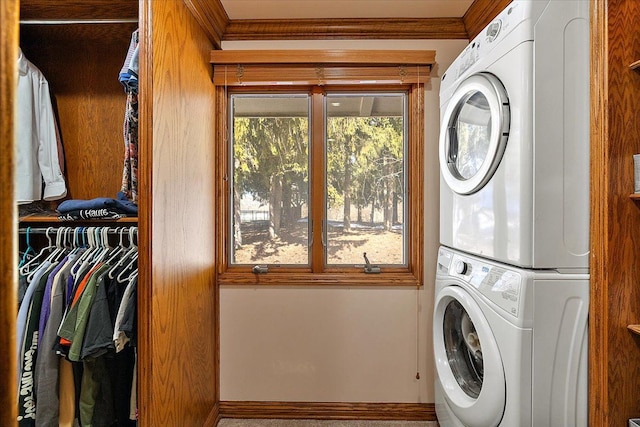 washroom featuring laundry area, ornamental molding, and stacked washer / dryer