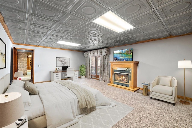 carpeted bedroom featuring an ornate ceiling, baseboards, and a glass covered fireplace