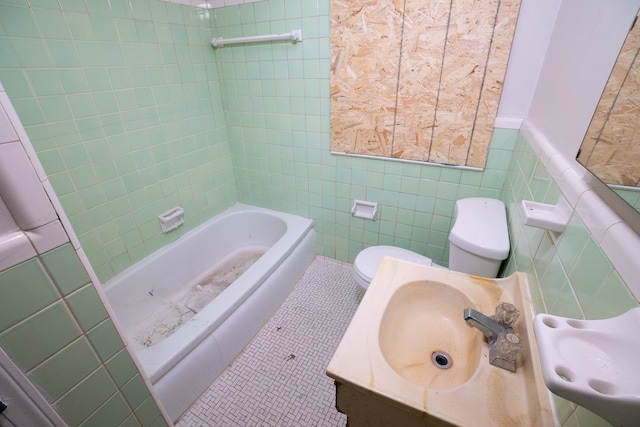 bathroom featuring a sink, tile walls, toilet, and tile patterned floors