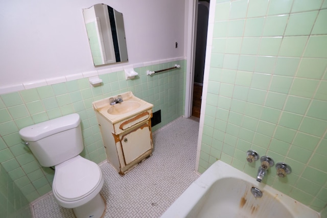 bathroom featuring tile walls, tile patterned floors, toilet, vanity, and a bath