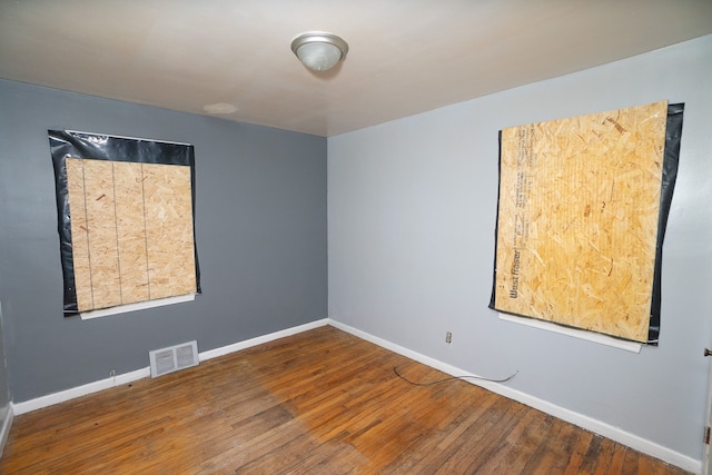 unfurnished room featuring visible vents, baseboards, and hardwood / wood-style flooring